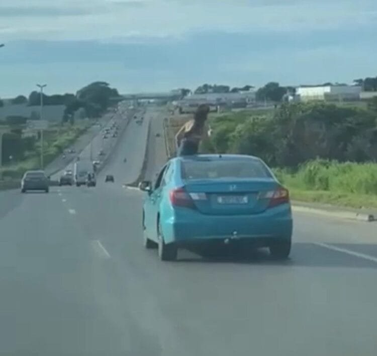 Jovem é flagrada no teto de carro em movimento na BR-153: imprudência com bebida na mão!